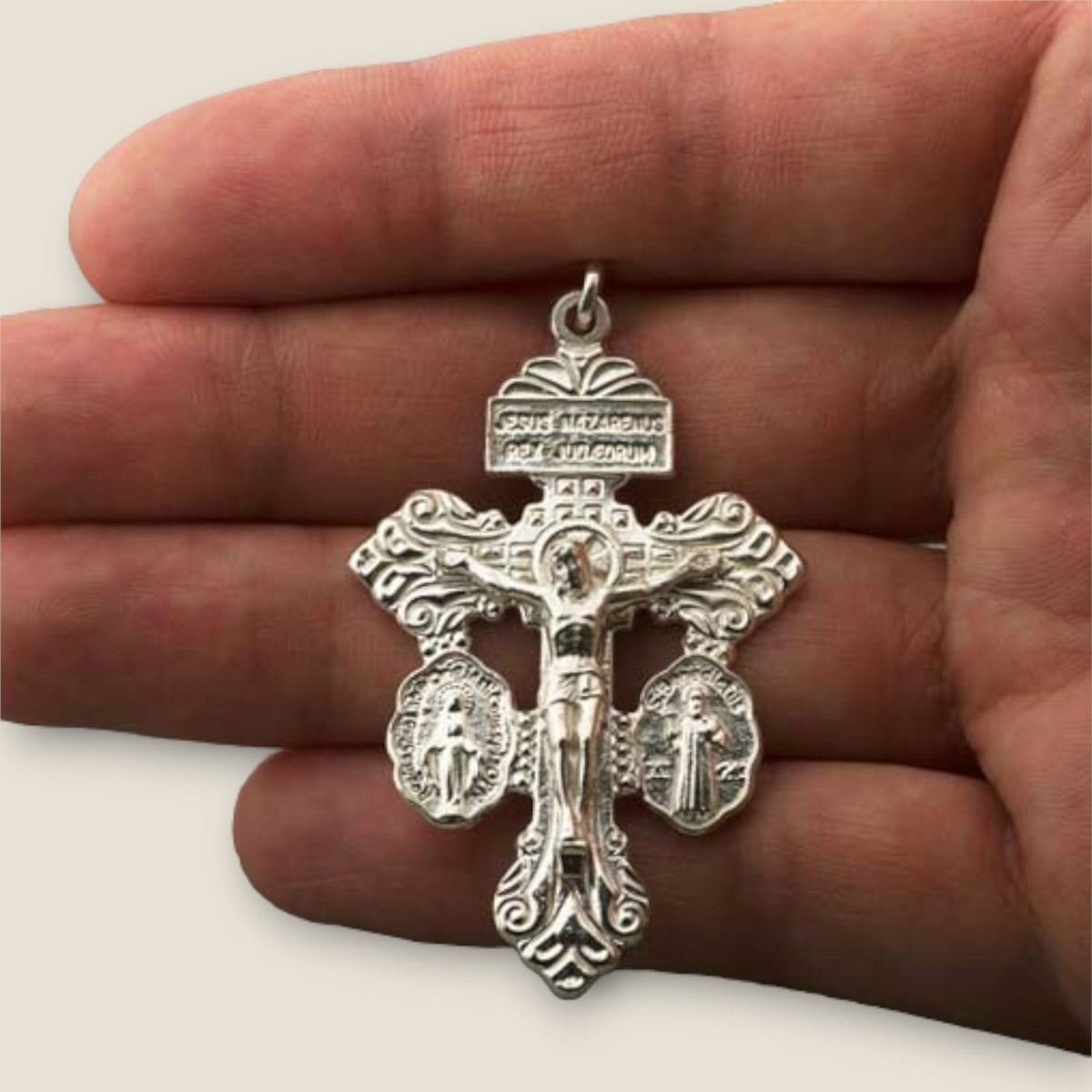 Cruz del Perdón en plata - sobre una mano