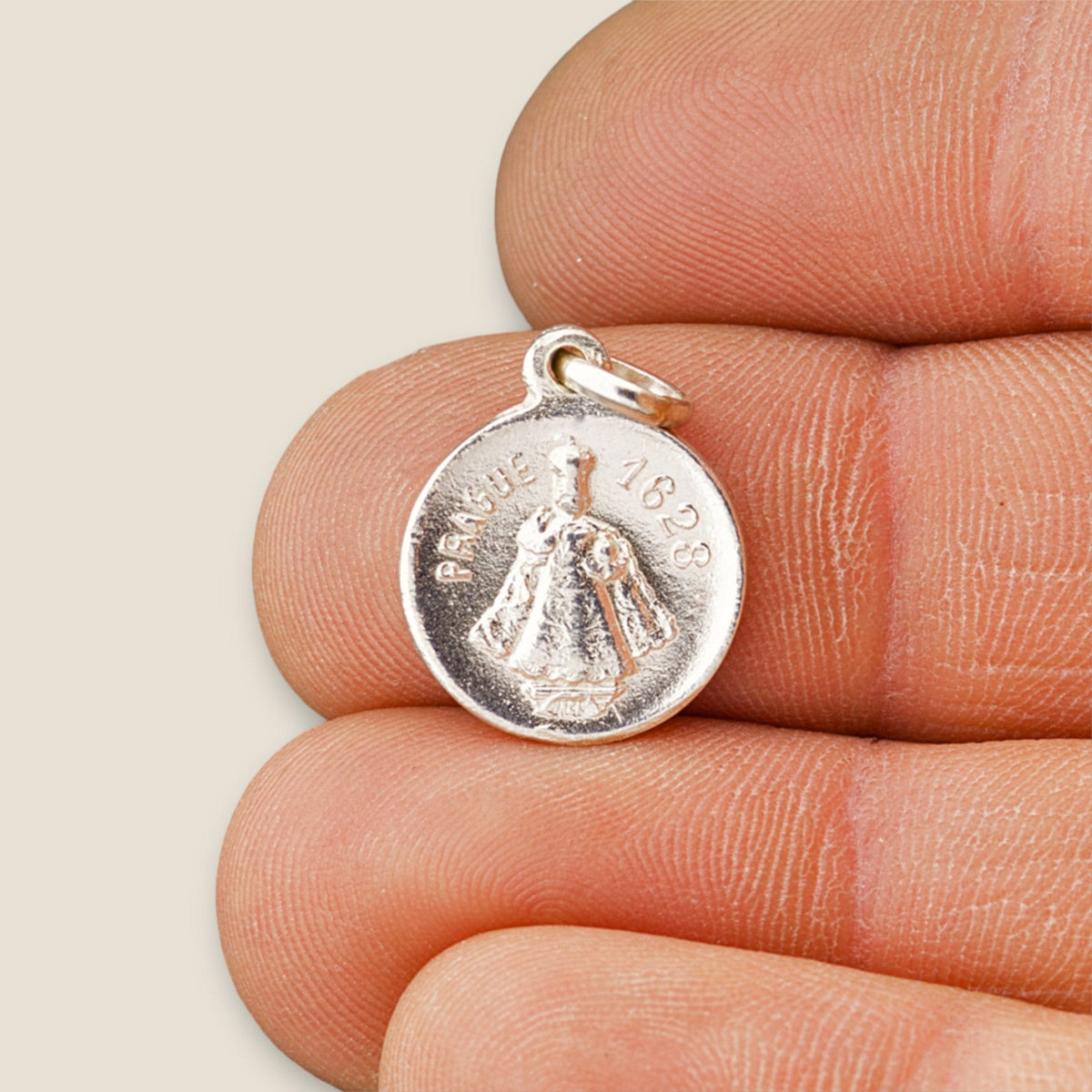 Medalla del Niño Jesús de Praga en plata - sobre una mano