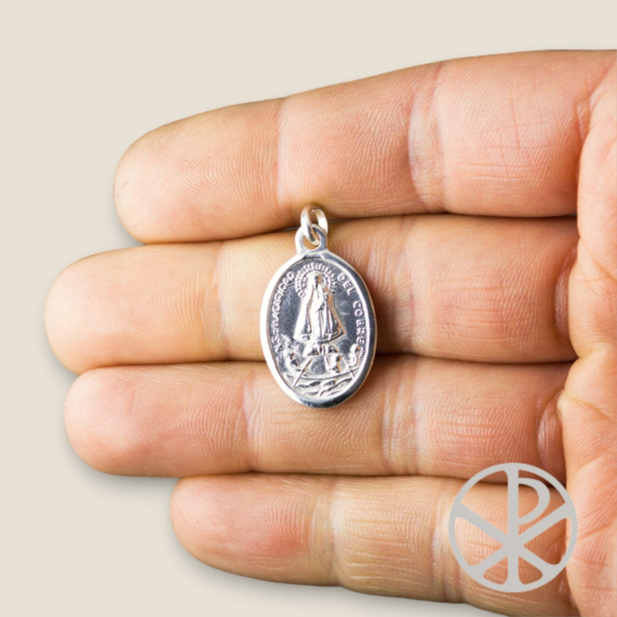 Medalla de Nuestra Señora de la Caridad del Cobre en plata - sobre una mano
