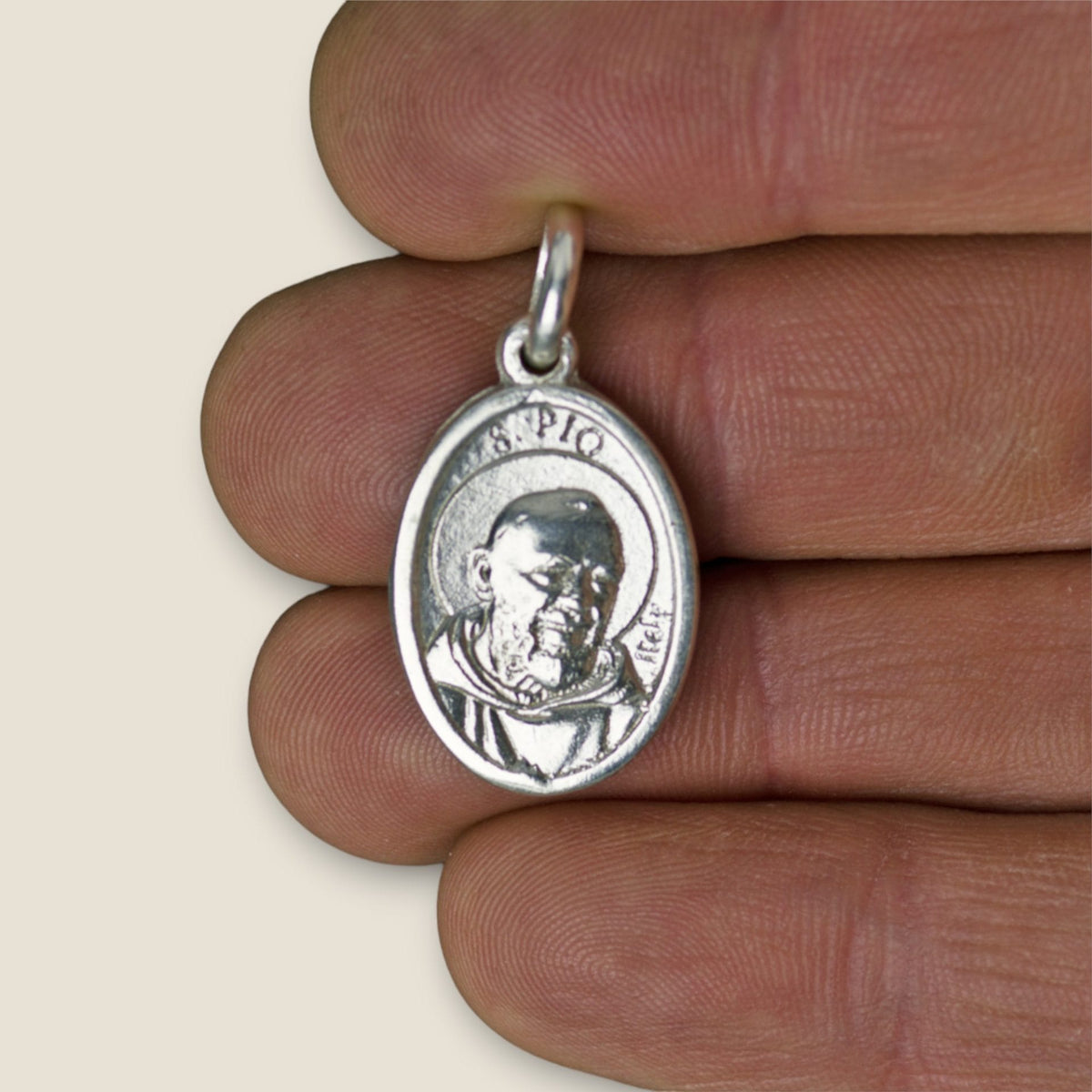 Medalla de Padre Pío en plata - sobre una mano