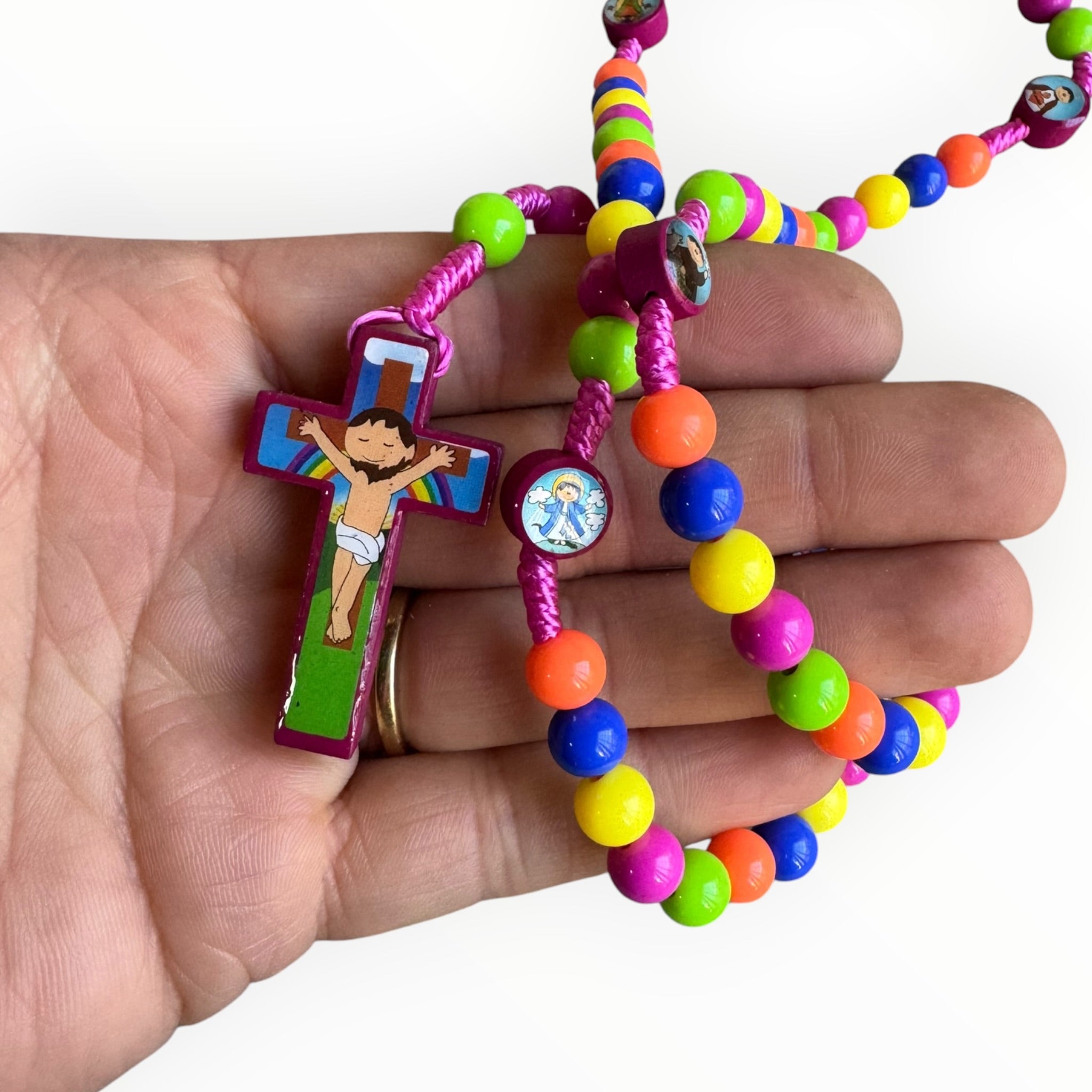 Rosario infantil multicolor con cuentas de plástico neón, medallas de santos ilustrados y crucifijo decorativo, ideal para primera comunión y catequesis Sobre una mano