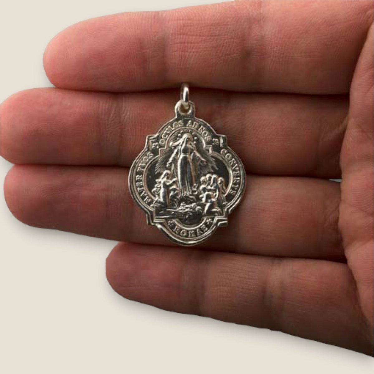 Medalla de la Virgen Inmaculada en plata - sobre una mano