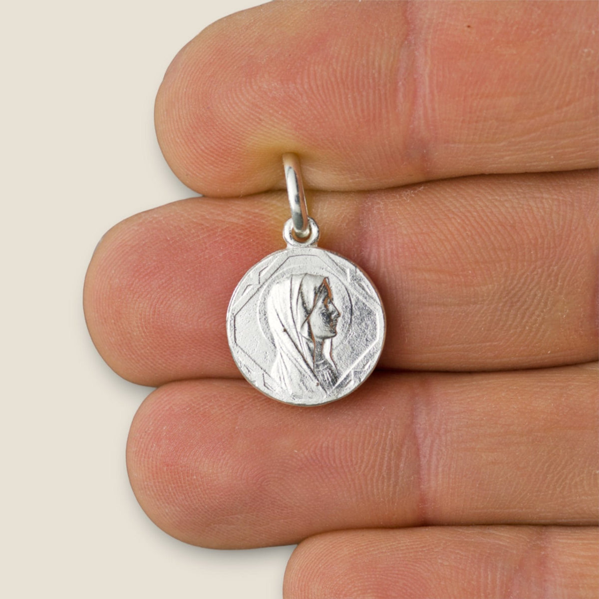 Medalla de la Virgen de Lourdes en plata - 14mm sobre una mano