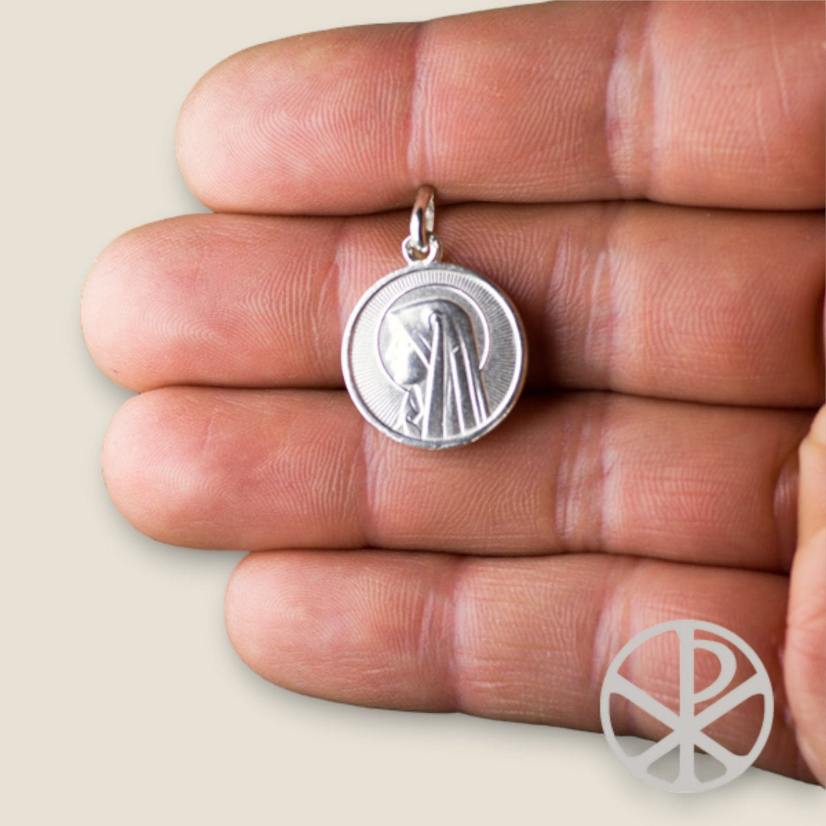 Medalla de la Virgen de Lourdes en plata - 18mm sobre una mano