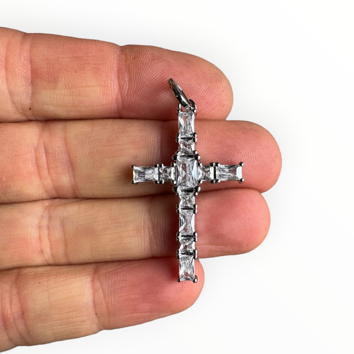 Cruz con circones blancos en plata - sobre una mano