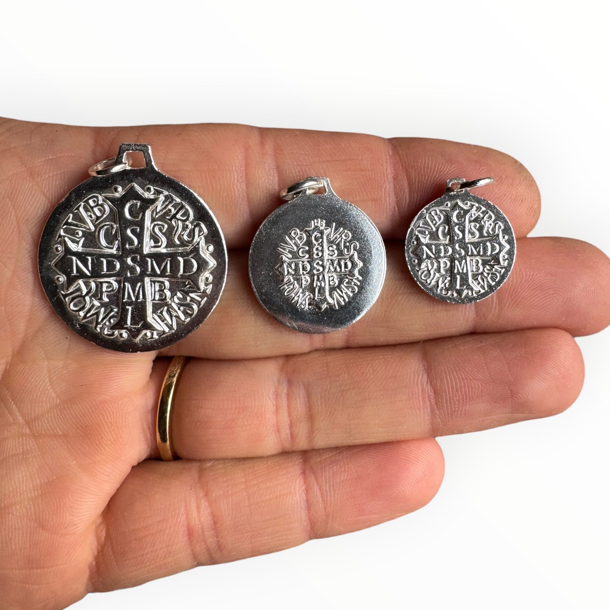 Medalla de San Benito en Plata estilo art deco sobre una mano por el revés