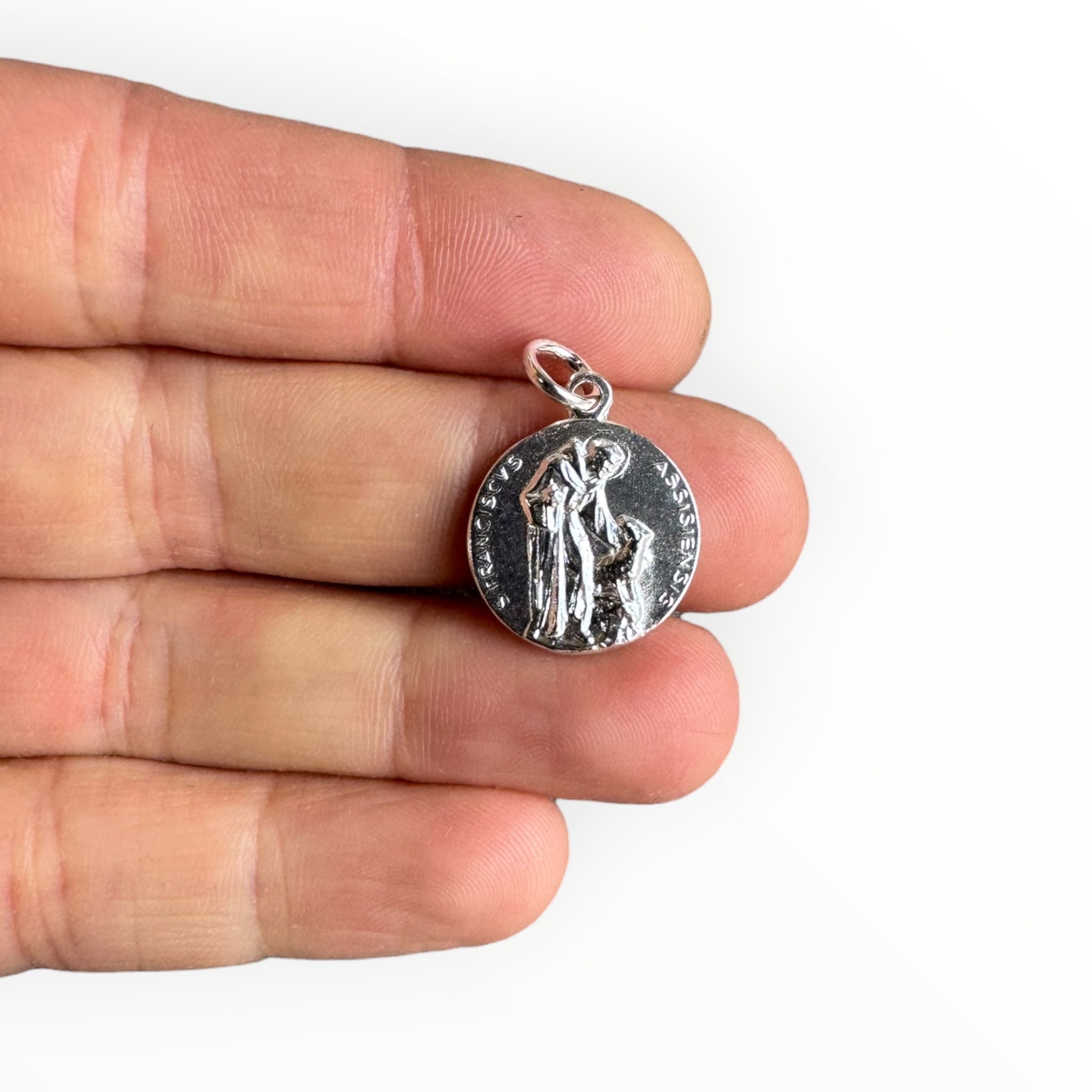Medalla de San Francisco de Asis de plata en una mano