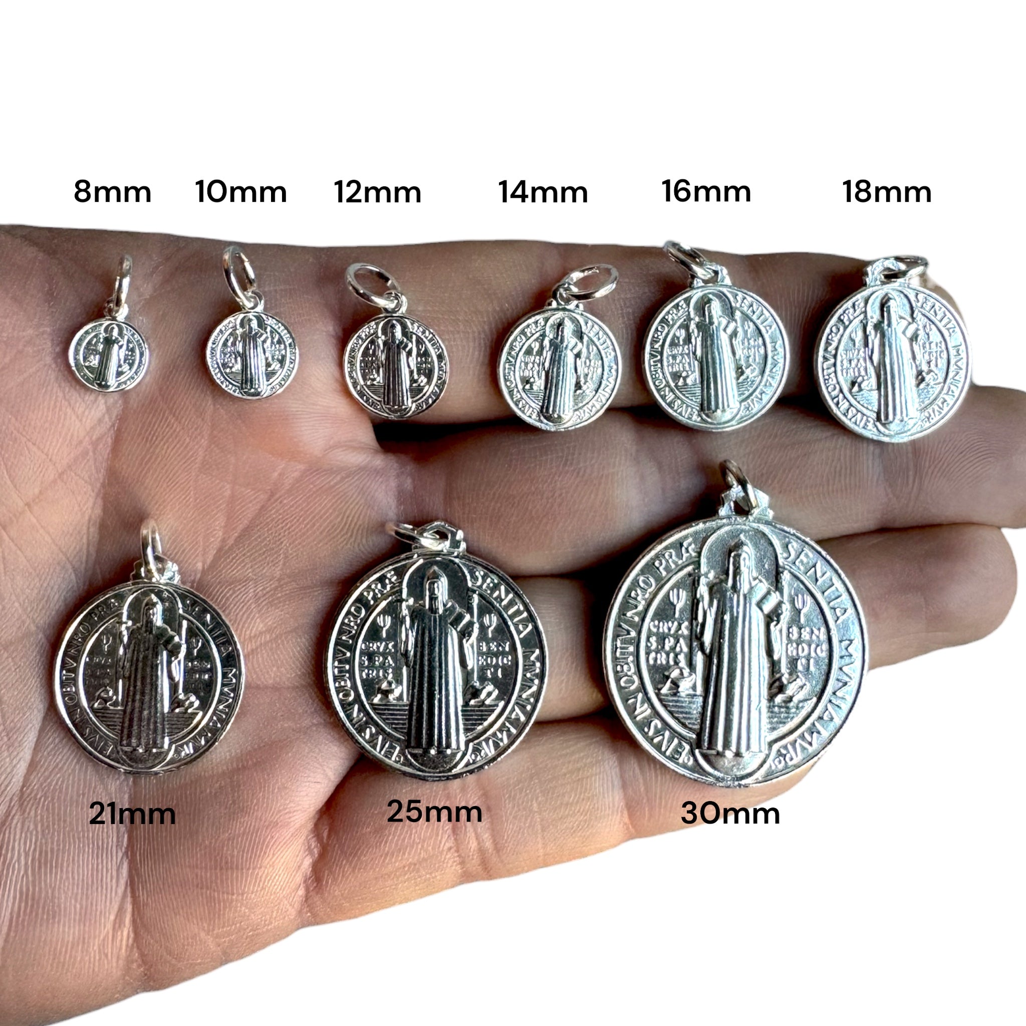 medallas de san benito en todos los tamaños sobre una mano