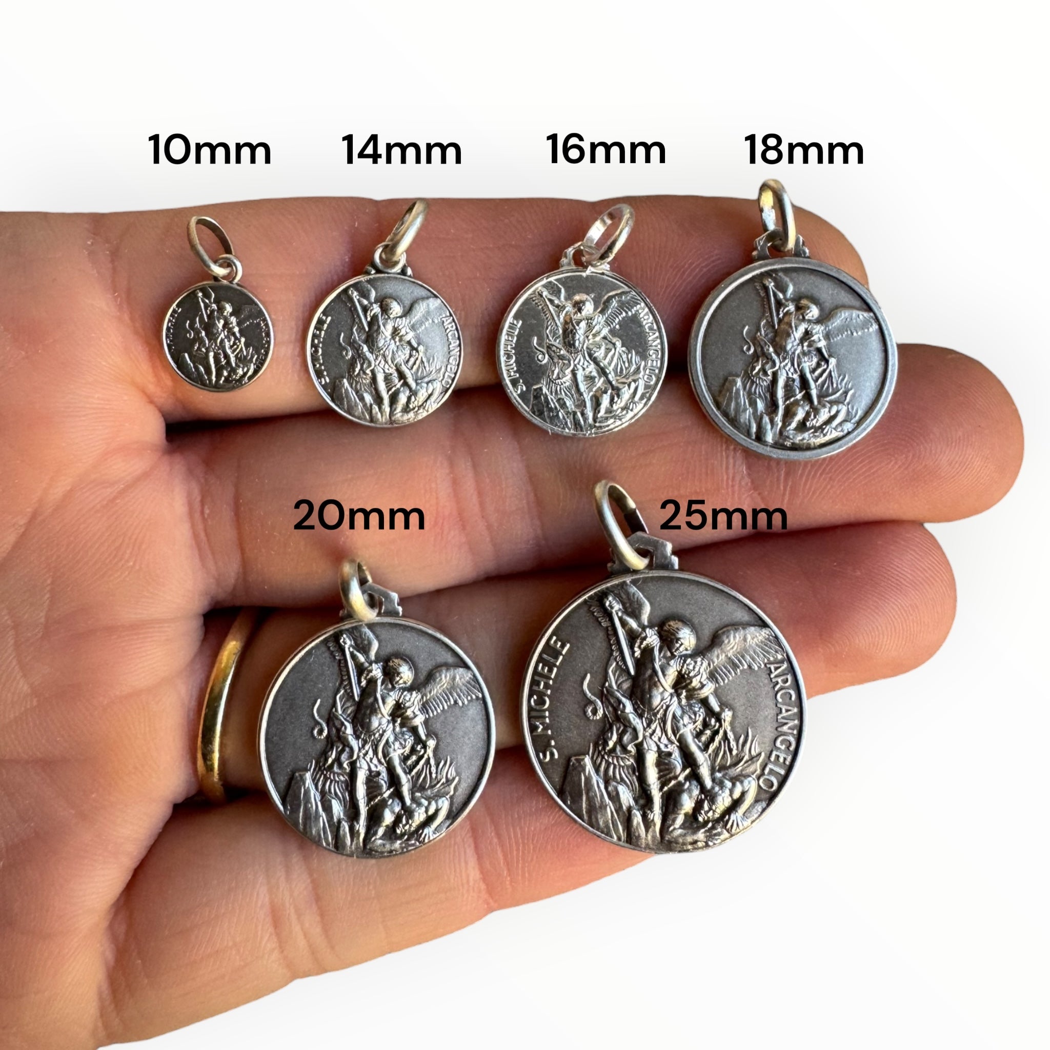 medallas de san miguel arcángel de plata tamaños comparados en una mano