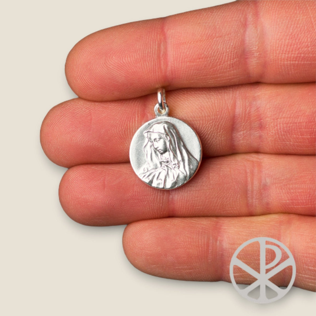 Medalla de la Virgen de los Dolores en plata - sobre una mano