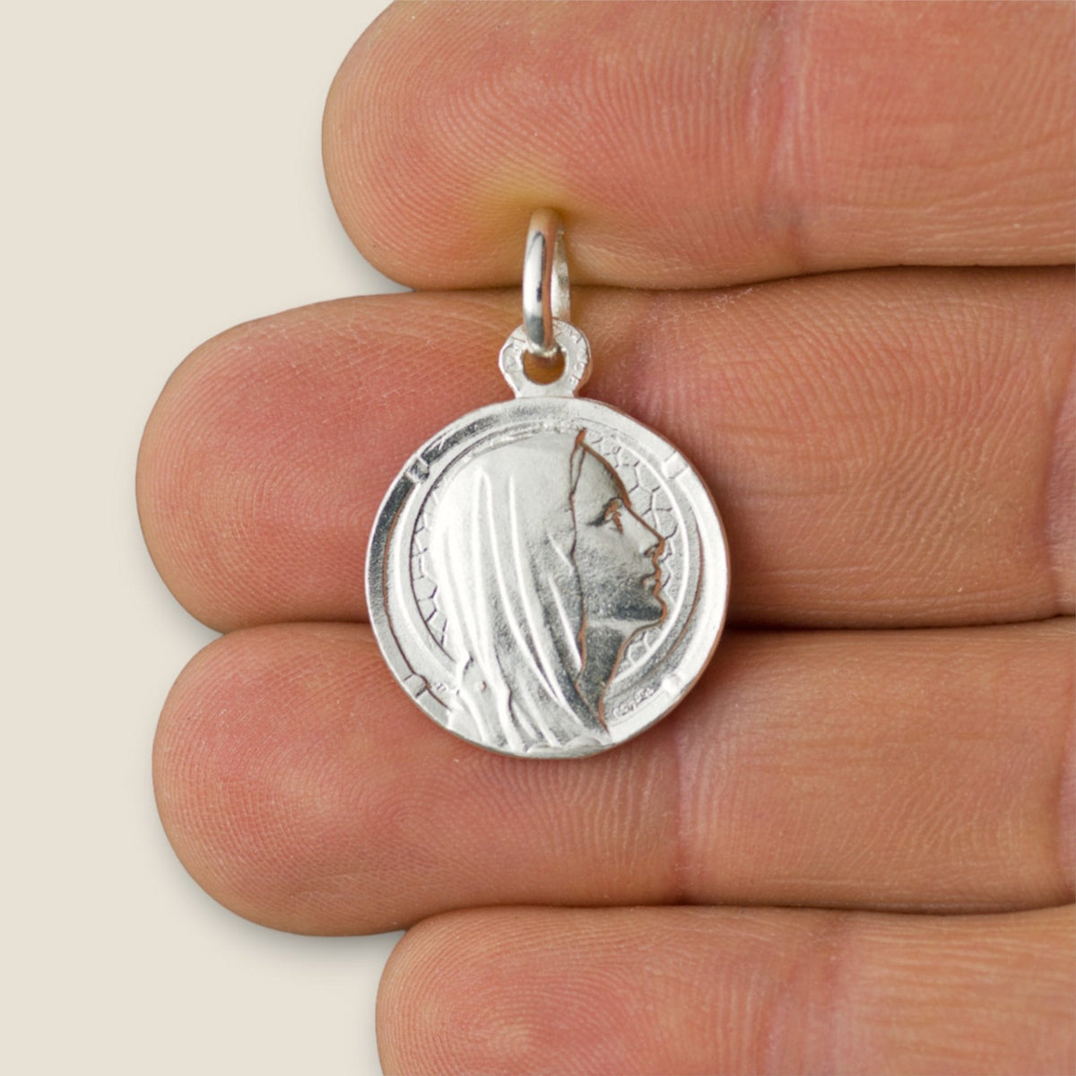 Medalla de la Virgen de Lourdes en plata - 17mm sobre una mano
