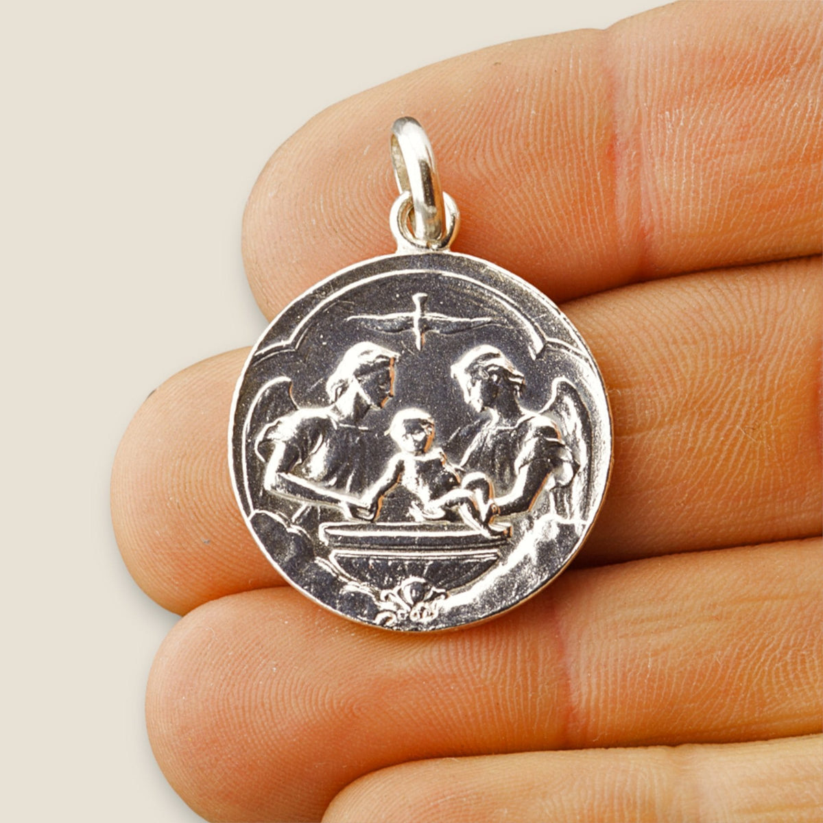 Medalla de Bautizo en plata - sobre una mano