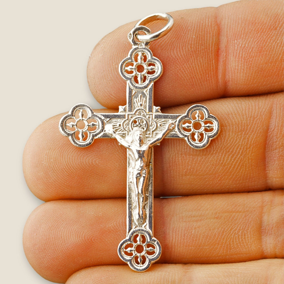 Cruz de plata calada con Cristo - sobre una mano