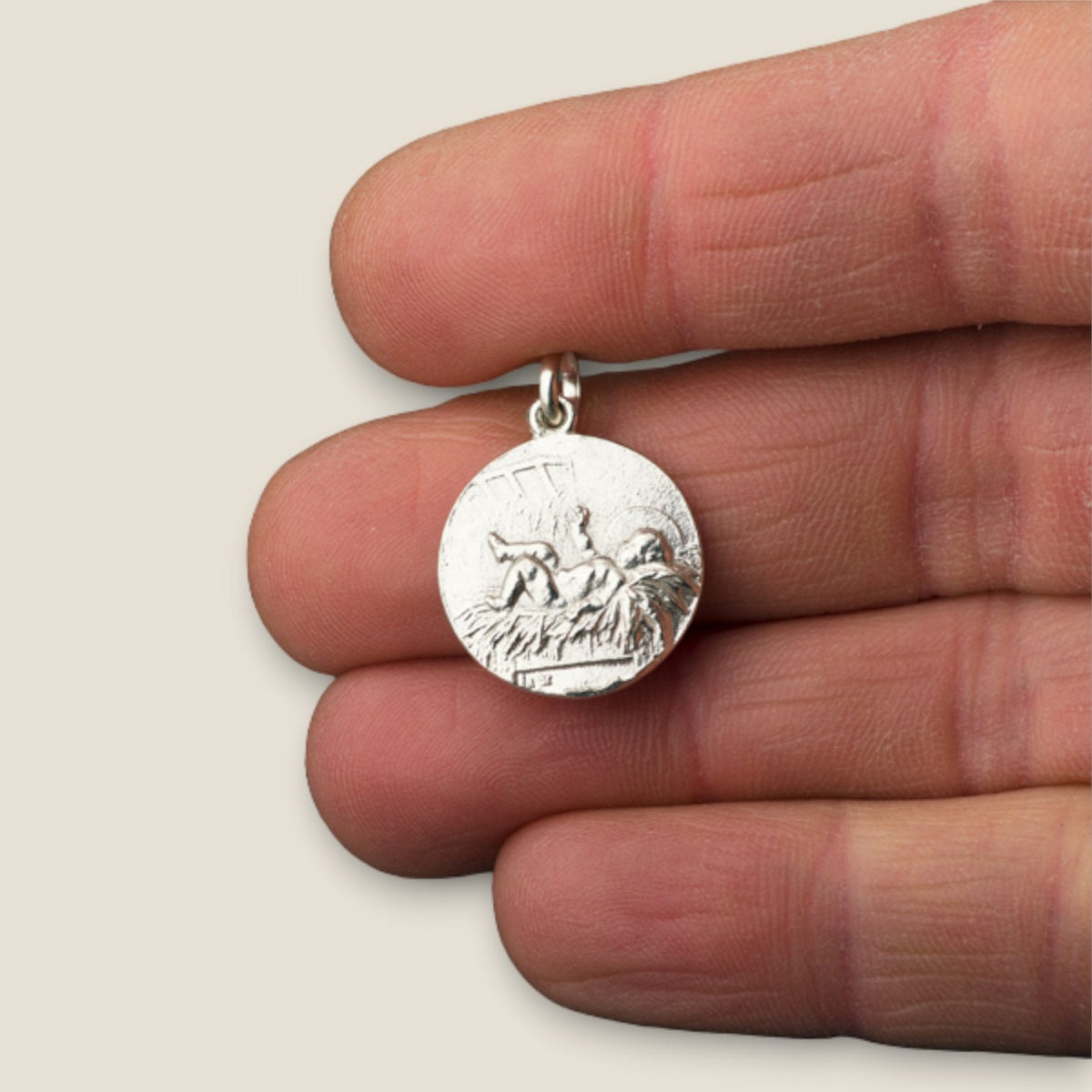 Medalla del Niño Jesús en plata - sobre una mano