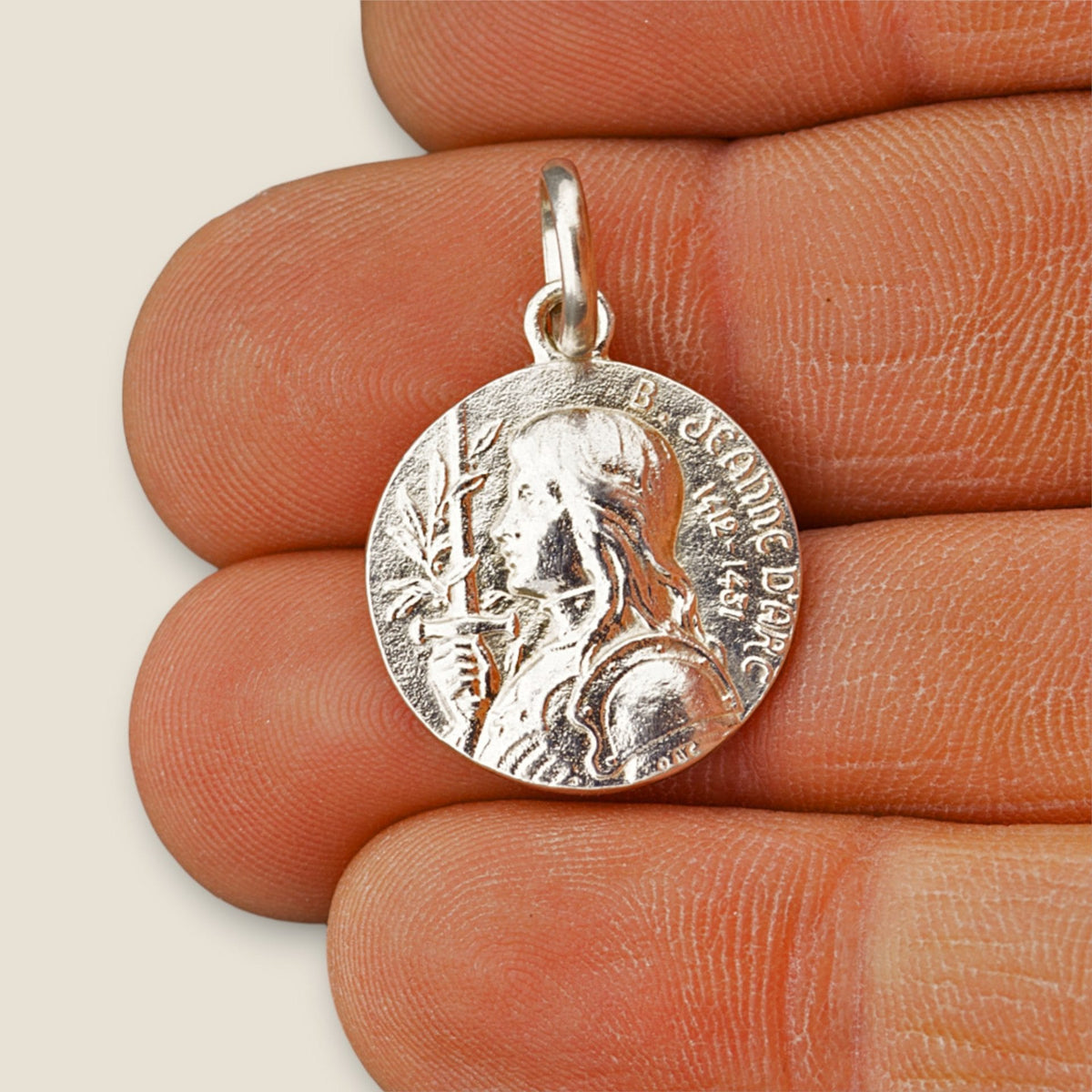 Medalla de Santa Juana de Arco en plata - 18mm sobre una mano