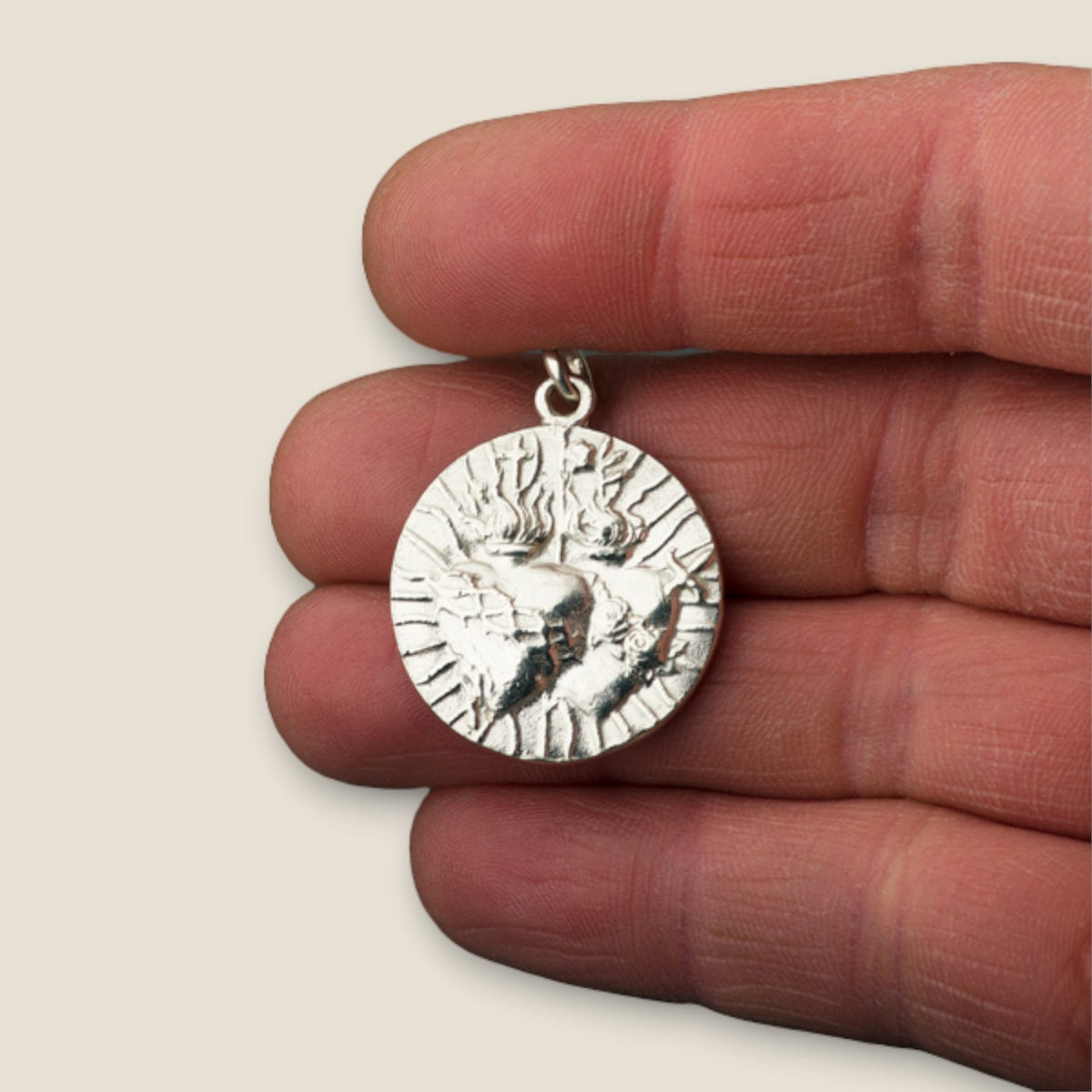Medalla Sagrados Corazones en plata - sobre una mano