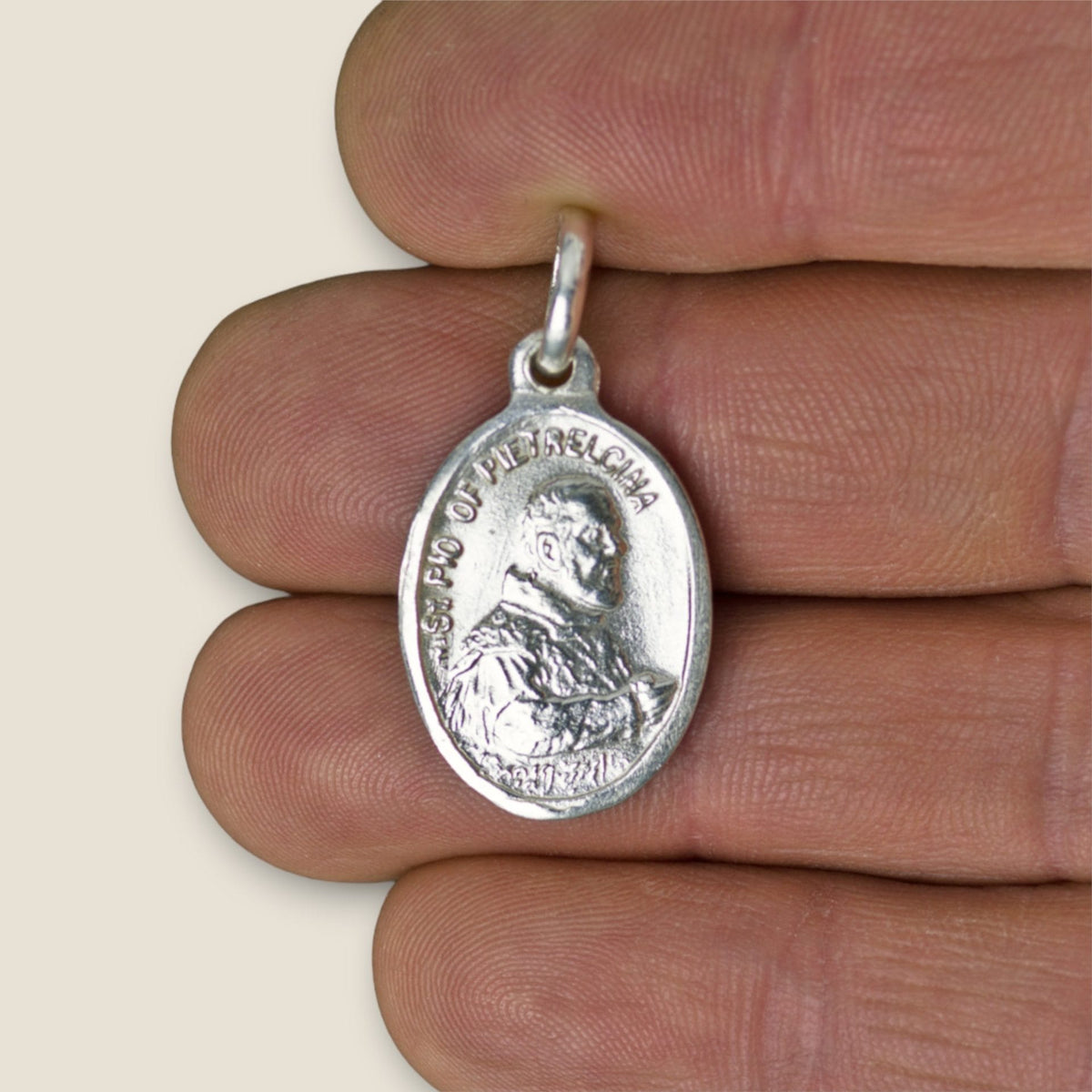 Medalla de Padre Pío en plata - sobre una mano