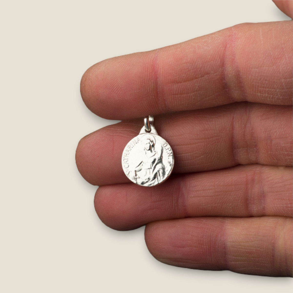 Medalla de Santa Catalina de Alejandría en plata - sobre una mano