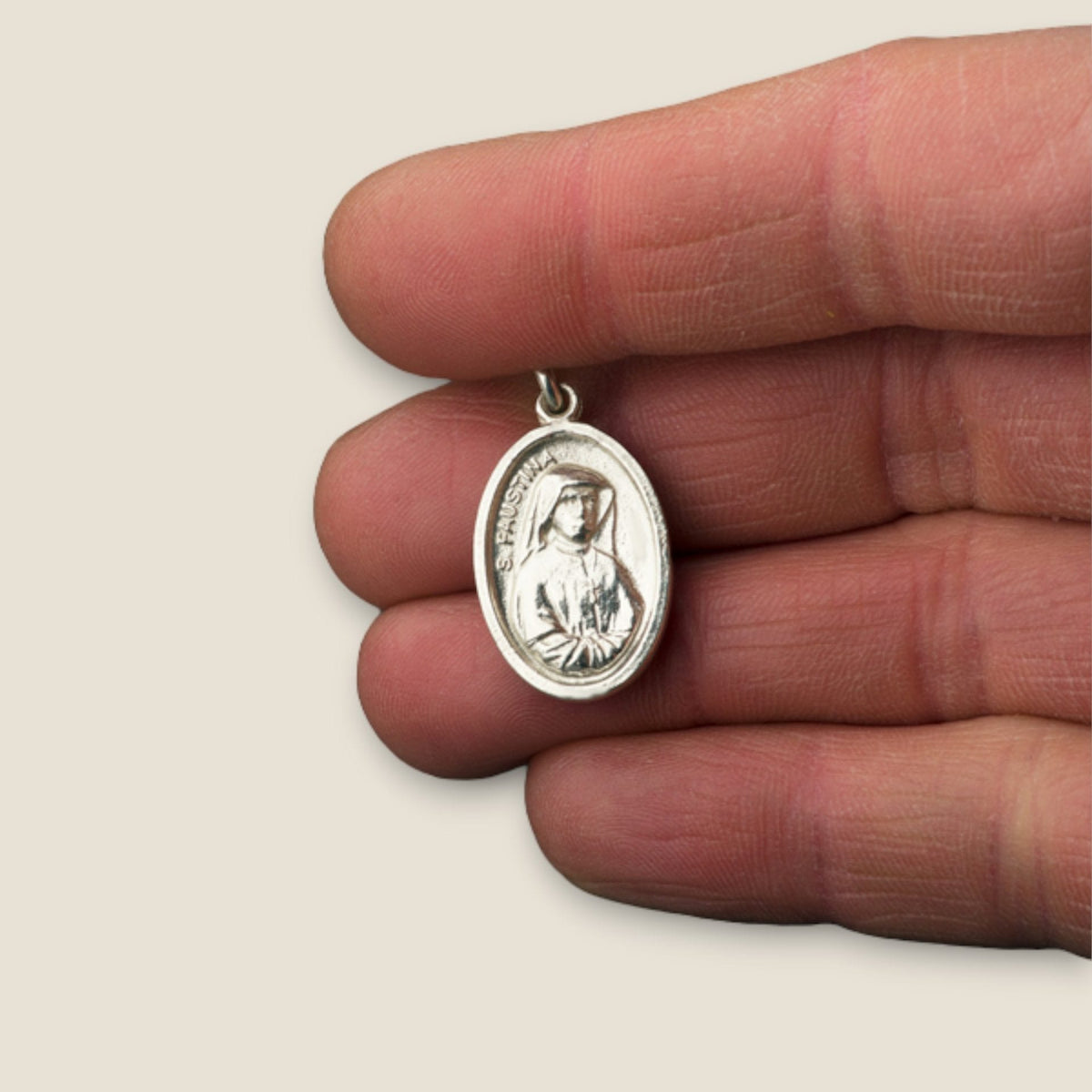Medalla de Santa Faustina y Jesús de la Divina Misericordia en plata - sobre una mano