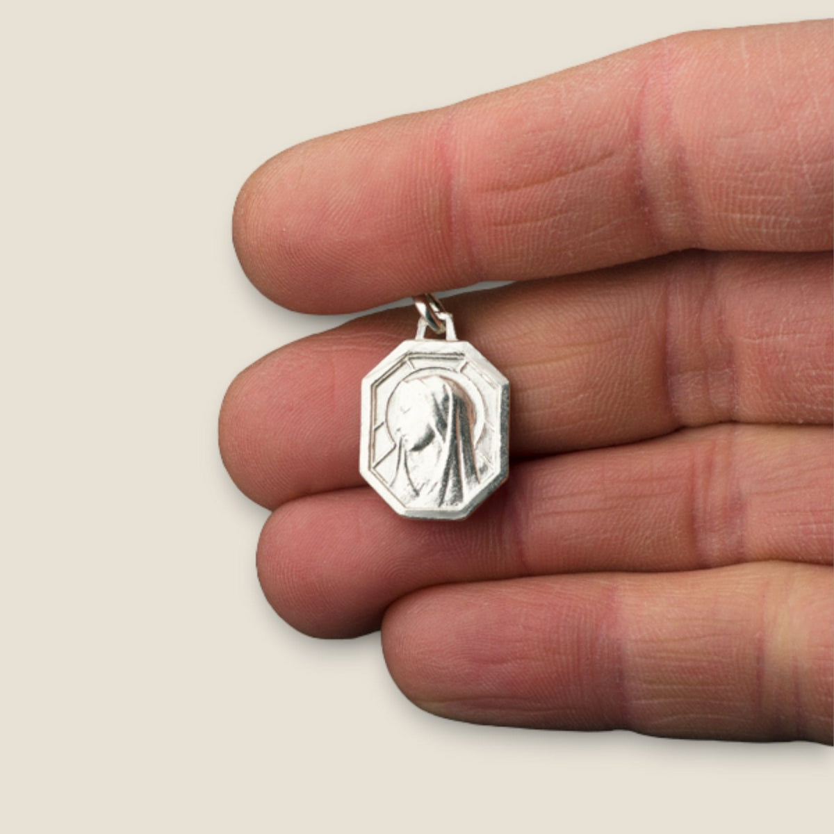 Medalla de la Virgen de Lourdes Octogonal en plata - 20mm sobre una mano