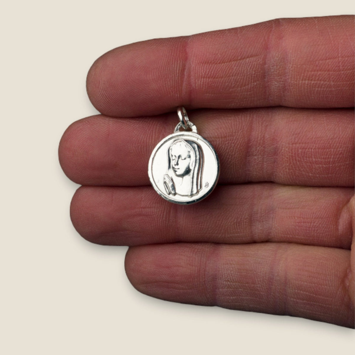 Medalla de la Virgen Niña en plata - sobre una mano