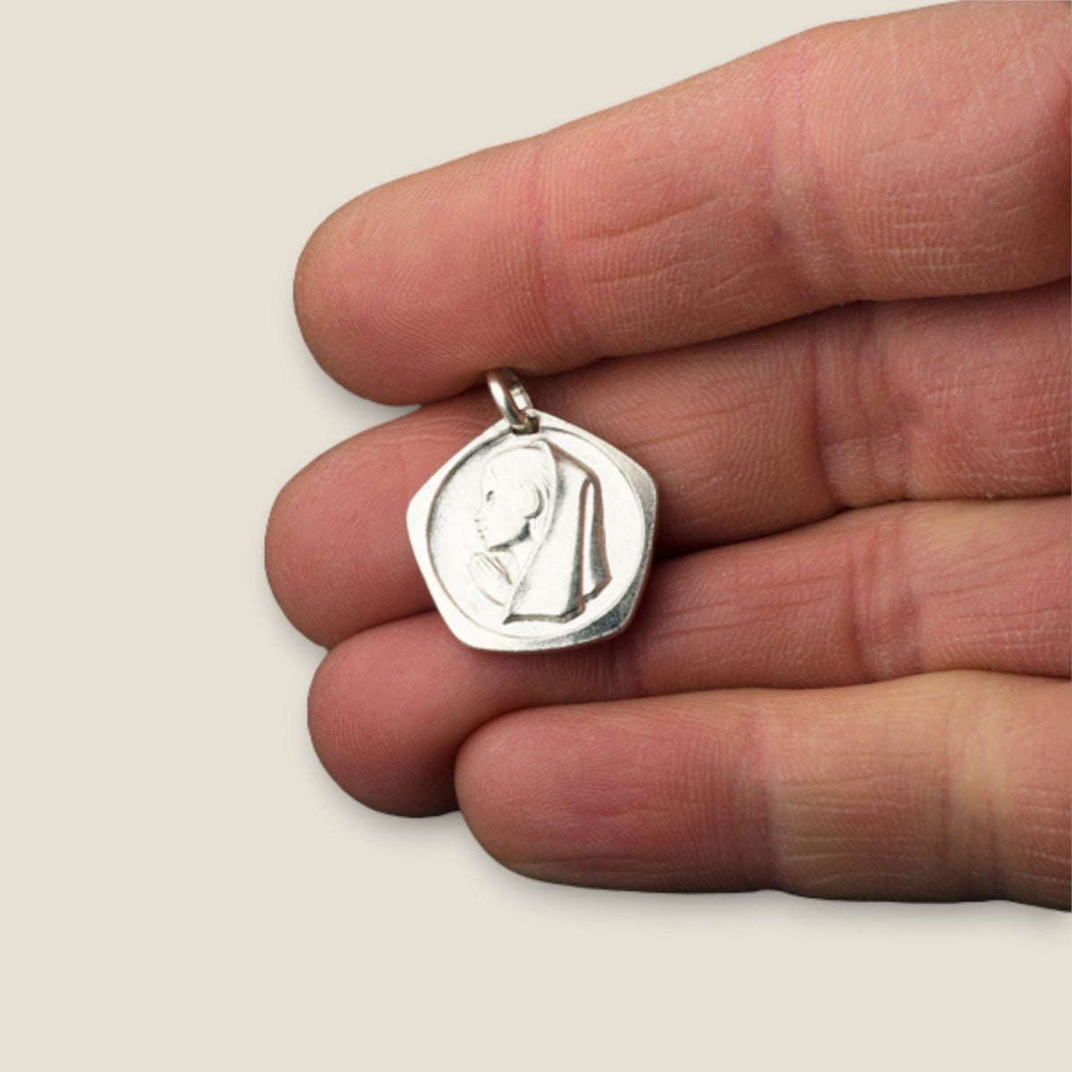 Medalla de la Virgen Niña en plata - sobre una mano