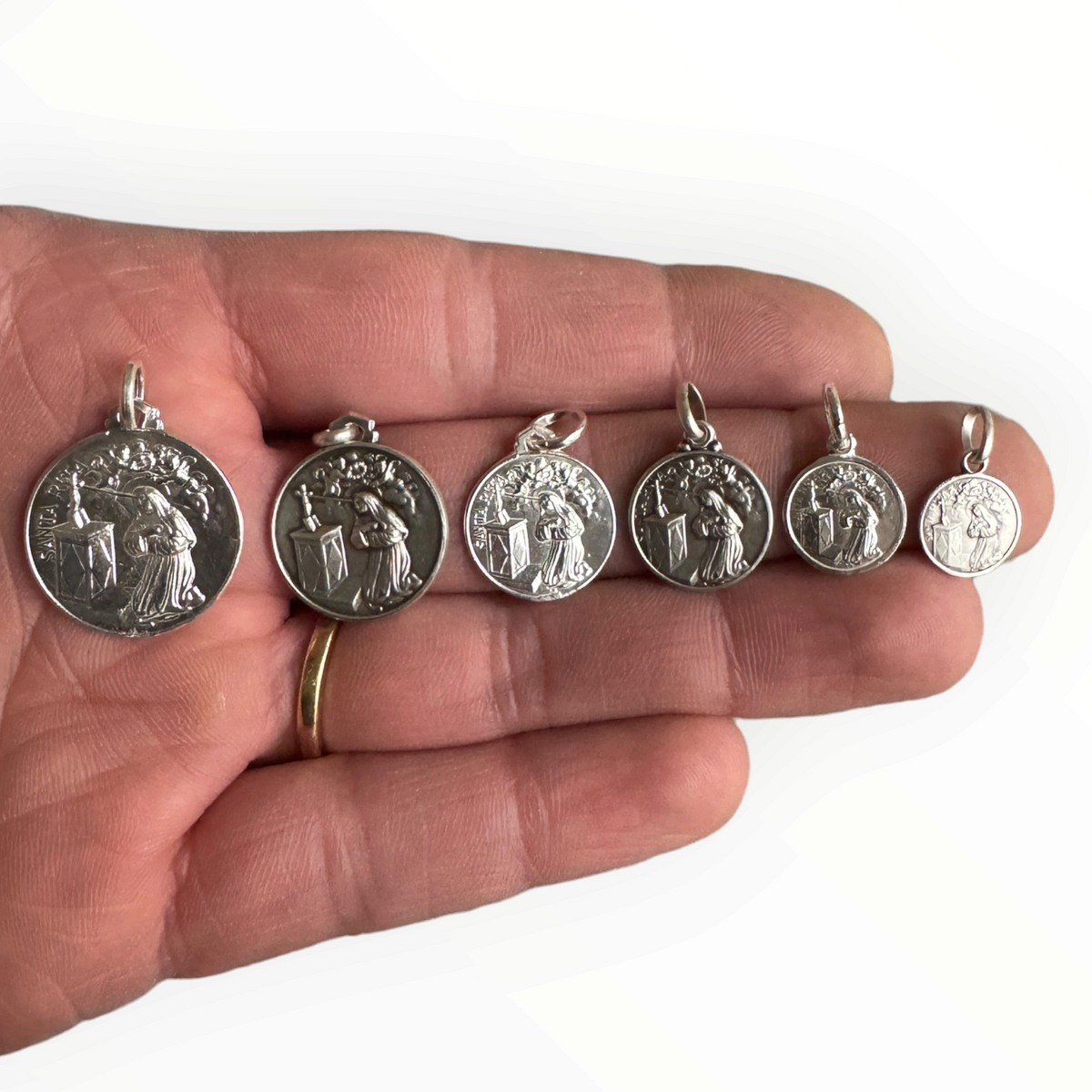 Medalla de Santa Rita de plata sobre mano 