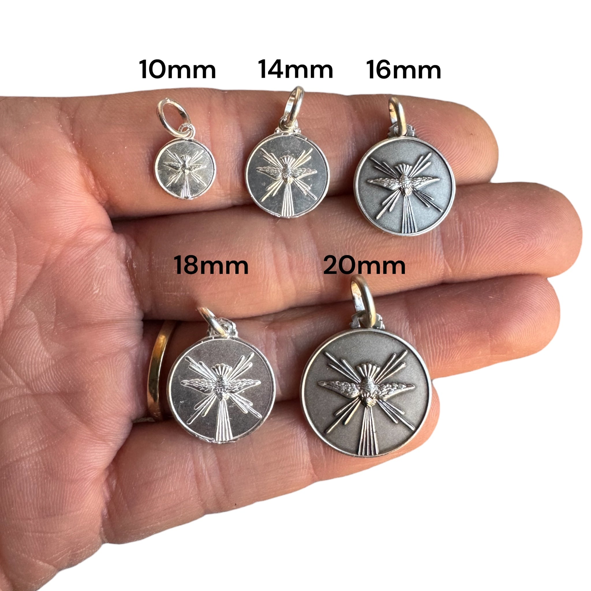 medallas de espiritu santo en plata sobre una mano para comparación