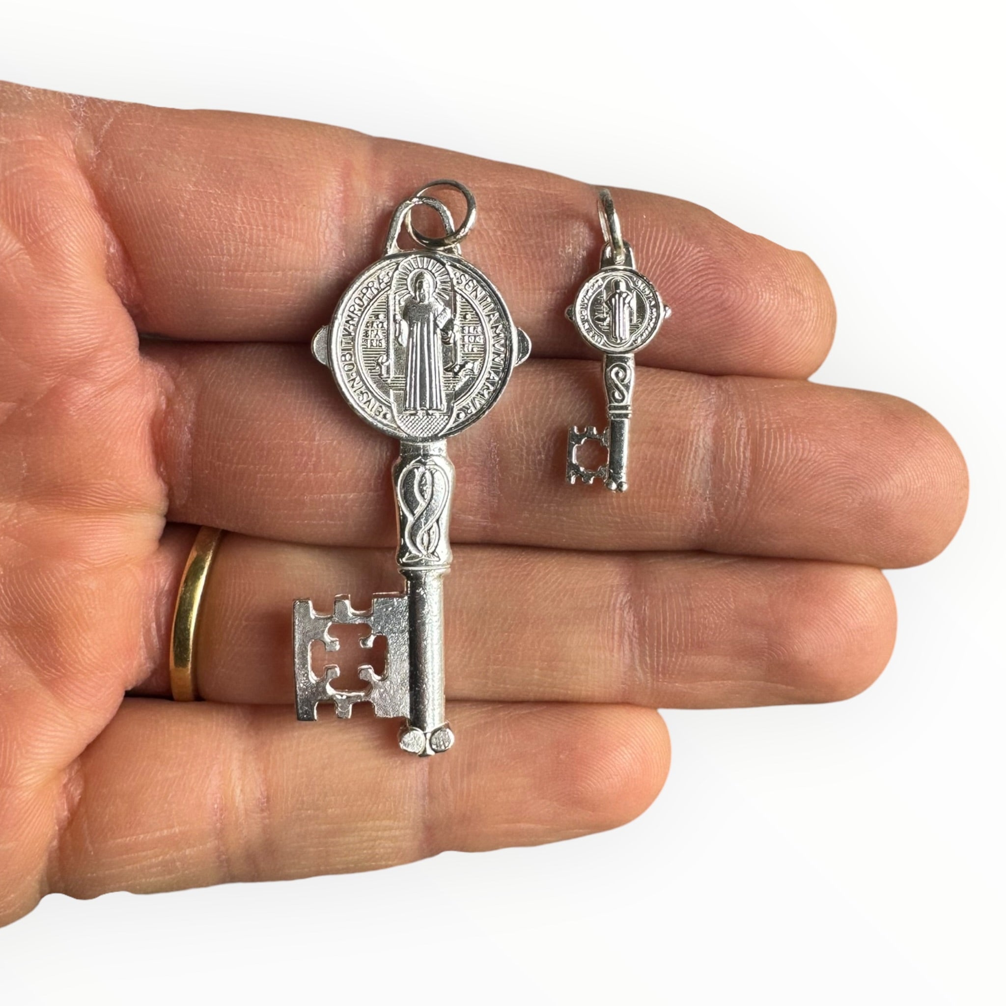 Medalla llave de San Benito de Plata sobre una mano 