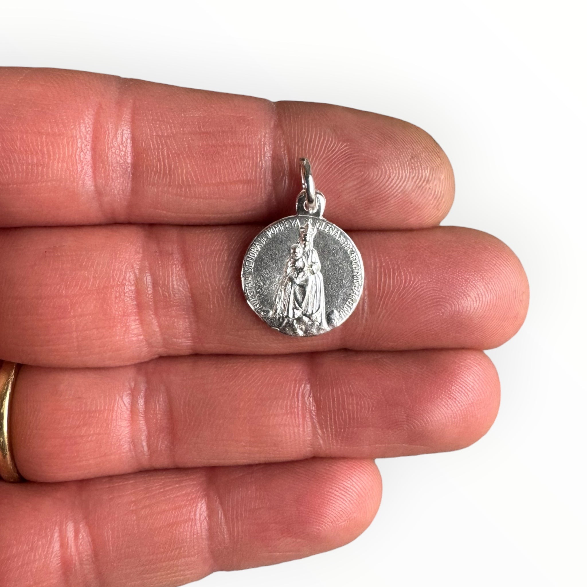 Medalla de la Virgen de Pompeya en plata sobre una mano